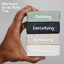 MARLOWE. Santal Scrub Soap Bar with natural exfoliants, featuring warm sandalwood scent and creamy lather in a rectangular shape.