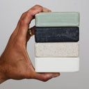 Hand holding four bars of MARLOWE. Soap